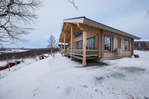 uma cabana de madeira na neve com chão coberto de neve em Arctic Aurora Borealis cottages em Nuorgam