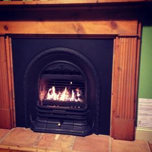 a black fireplace with a fire in it at Tramway Cottage in Strahan