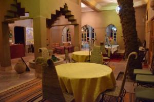 Habitación con 2 mesas, sillas y árboles en Hotel Carrefour des Nomades en Mhamid