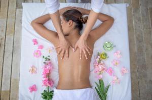 Entremonte Wellness Hotel and Spa في أبولو: امرأة مستلقية على سرير مع زهور