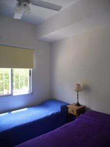 Un dormitorio con una cama azul y una ventana. en Los Amigos del Pinar, en Valeria del Mar