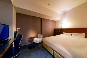 ein Hotelzimmer mit einem Bett, einem Schreibtisch und einem Fernseher in der Unterkunft JR Inn Sapporo in Sapporo