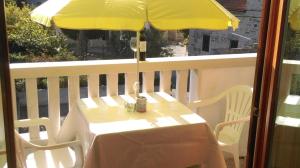 a table with a yellow umbrella on a balcony at Guest House Marija in Sumartin