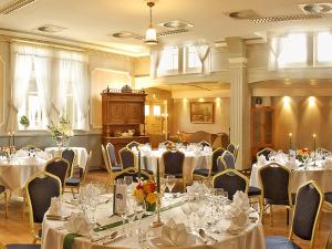 a room filled with tables and chairs with white table cloth at Landgasthaus & Hotel Lindenhof in Königslutter am Elm
