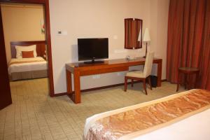 a hotel room with a desk with a television and a bed at Super House International in Beijing