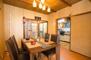 a dining room with a table and chairs and a kitchen at Aoi-Riverside Old Townhouse in Kyoto