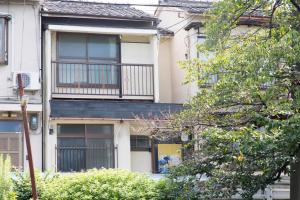 京都的住宿－葵芳河畔老聯排別墅度假屋，公寓大楼设有阳台和树木