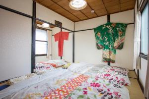 京都的住宿－葵芳河畔老聯排別墅度假屋，卧室配有两张床,墙上挂着衣服
