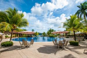 a resort pool with tables and chairs and palm trees at Los Suenos Resort Colina 5E two bedroom by Stay in CR in Herradura