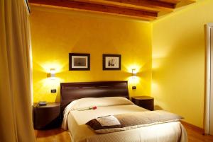 a yellow bedroom with a bed and two lamps at Hotel Fontana Santa in Grumello del Monte