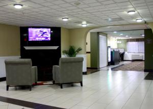 a lobby with two chairs and a flat screen tv at AmericInn by Wyndham Woodstock IL in Woodstock