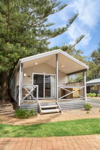 una pequeña casa blanca con un árbol en Kendalls Beach Holiday Park en Kiama