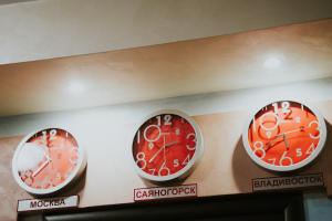 tres relojes en una pared en una habitación en Sayanogorsk Hotel, en Sayanogorsk