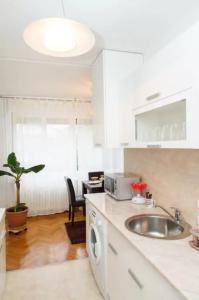 eine weiße Küche mit einem Waschbecken und einem Tisch in der Unterkunft Modern Cozy Apartment in Belgrad + 6 Fotos