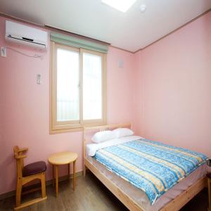 1 dormitorio con cama, ventana y silla en You&I Guesthouse en Jeju