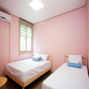 two beds in a room with a window at You&I Guesthouse in Jeju