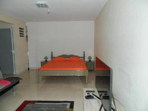 Schlafzimmer mit einem Bett mit roter Bettwäsche und einer roten Decke in der Unterkunft Madiana plage in Schœlcher