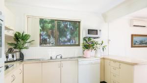 a white kitchen with a sink and a window at Driftwood Beachfront @ Vincentia in Vincentia