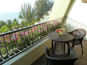 a table and two chairs on a balcony with flowers at PARKROYAL Penang Resort in Batu Ferringhi