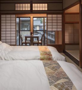 a room with two beds and a balcony with a table at Marikoji Inn Kyoto in Kyoto