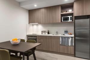 a kitchen with a table and a refrigerator at Quest Innaloo in Perth