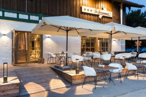 un patio con mesas, sillas blancas y sombrillas en Hotel Hörterer Der Hammerwirt en Siegsdorf