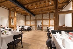 a restaurant with white tables and chairs and wooden ceilings at Kloster Dornach / Basel in Dornach