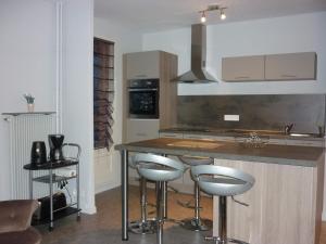 eine Küche mit einer Theke und Hockern in einem Zimmer in der Unterkunft L'Orée du Parc à Belfort in Belfort