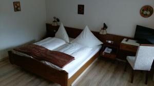 a bedroom with a bed with white sheets and a desk at Hotel-Restaurant Jägerhof in Unterreichenbach