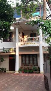 a white house with columns and a porch with chairs at Veda Vihar Homestay & Yoga Centre in Cochin