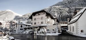 ein großes Gebäude im Schnee neben einem Fluss in der Unterkunft Hotel Gramaser in Ischgl