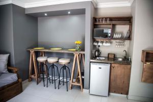 a kitchen with a bar with stools and a sink at Touching Senses Garden Cottages in Bloemfontein