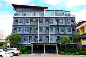 碧差汶The D257 Hotel的一座高大的蓝色建筑,前面有汽车停放