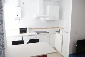 Biała kuchnia z białymi szafkami i białym stołem w obiekcie FANTÁSTICO PISO, JUNTO AL TEATRO FALLA Y A LA PLAYA w Kadyksie