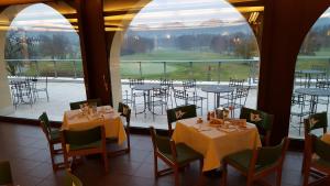ein Esszimmer mit Tischen und Stühlen und einem großen Fenster in der Unterkunft Asolo Golf Club in Cavaso del Tomba