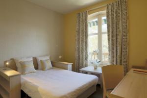 a bedroom with a white bed and a window at Logis Les Loges du Parc in La Roche-Posay