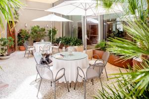 a restaurant with white tables and chairs and plants at Hotel Dei Fiori Restaurant - Meeting & Spa in Alassio