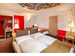 a hotel room with two beds and a red chair at Swiss Night by Fassbind in Zürich