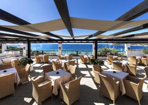 
a dining area with tables, chairs and umbrellas at Colonna Grand Hotel Capo Testa in Santa Teresa Gallura
