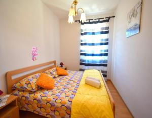 a bedroom with a bed with orange pillows and a window at Apartments Ivanka in Malinska