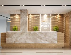 a room with a reception counter with potted plants at Renion Park Hotel in Almaty