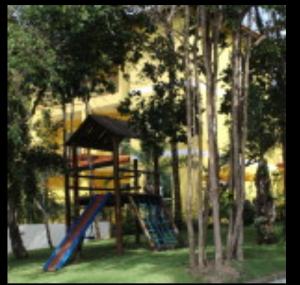 a playground with a slide in a park with trees at Vila Verona in Praia do Forte