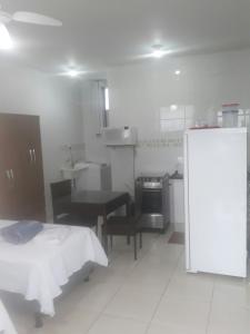 a kitchen with a bed and a table and a refrigerator at Flat Econômico Uberlândia in Uberlândia