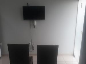 a room with two chairs and a flat screen tv at Flat Econômico Uberlândia in Uberlândia