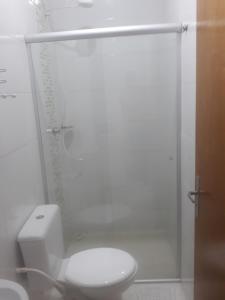 y baño blanco con aseo y ducha. en Flat Econômico Uberlândia, en Uberlândia