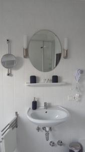 W białej łazience znajduje się umywalka i lustro. w obiekcie Hotel Piano w mieście Bergen