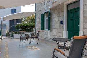 een patio met stoelen en tafels en een groene deur bij Studio apartment Džapo in Split