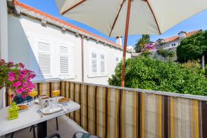 a balcony with a table and an umbrella at Apartments Villa Eta in Cavtat