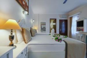 a large white bed with a lamp and flowers on it at La Paloma Hotel in Antalya