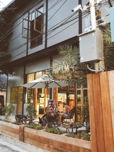 dos personas sentadas en sillas frente a un edificio en Bloom Cafe & Hostel en Ko Lipe